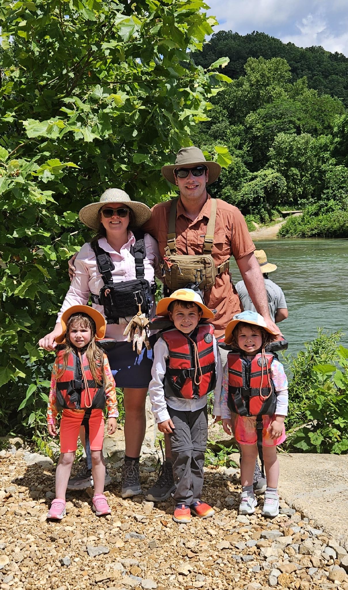 The Kingdom Overland family together beside the river in outdoor gear